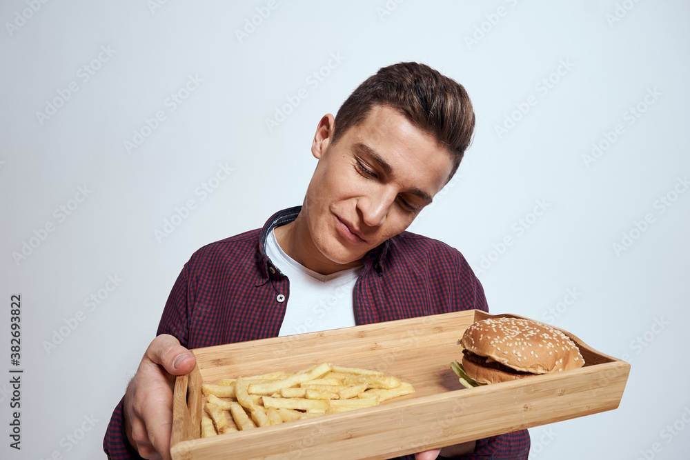 Man eating wooden pallet fast food french fries hamburger diet food restaurant light background Man eating wooden pallet fast food french fries hamburger diet food restaurant light background