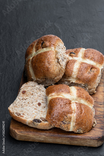 Easter wholemeal hot cross buns on wooden board on black stone background photo