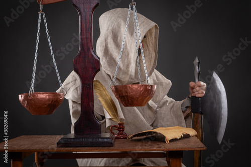 Halloween concept. The executioner of the holy inquisition with an ax weighing other people's sins