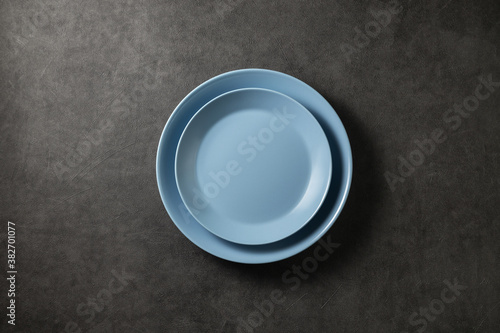 two beautiful blue modern plates on a dark gray concrete background, top view
