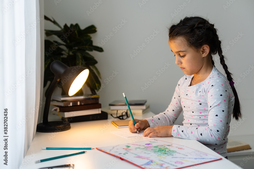 a child girl doing homework writing and reading at home