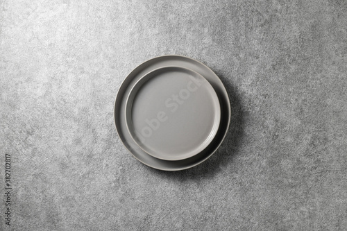 two beautiful gray plates on a gray concrete background, top view 