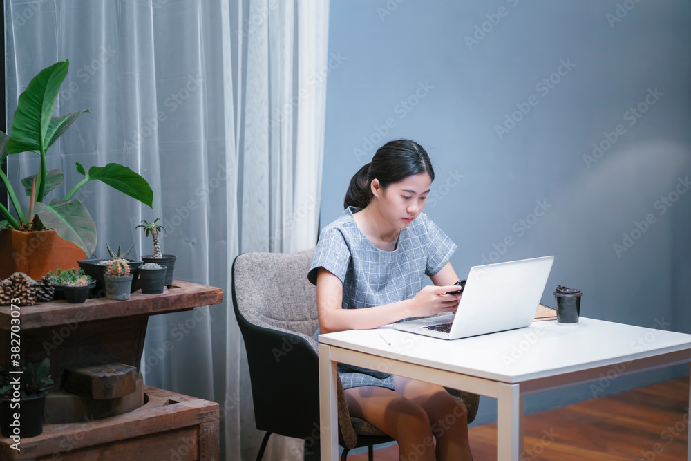 Asian attractive businesswoman work from home office small business owner planning organizing messaging contacting people using smart mobile phone computer technology information working late night