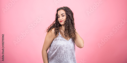 A beautiful young woman on a pink background in the studio.