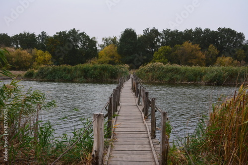 A small wooden bridge connects the banks of a shallow steppe river. photo