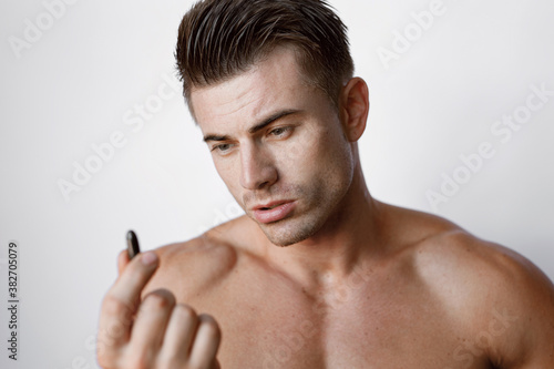 Muscular sexy model sports young man on white background. Portrait of beautiful smiling healthy guy holding a pill in his hand.