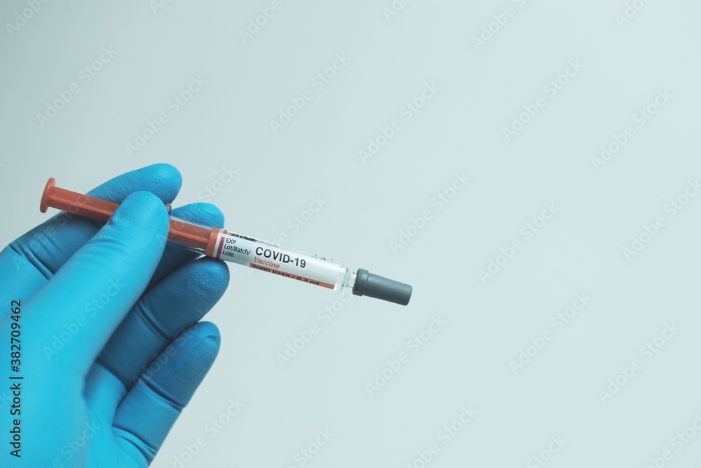 Obraz premium Doctor hand with blue gloves and Covid-19 vaccine