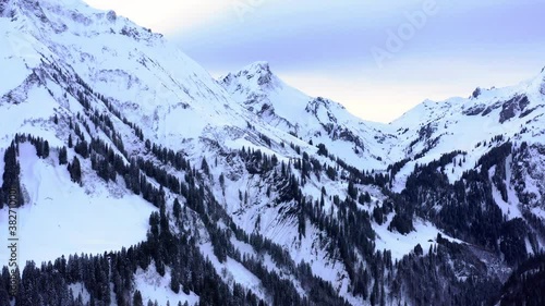 snow covered mountains in winter. Valley view with snow in the alps. Drone flight. Blue cloudy sky and snowy peaks