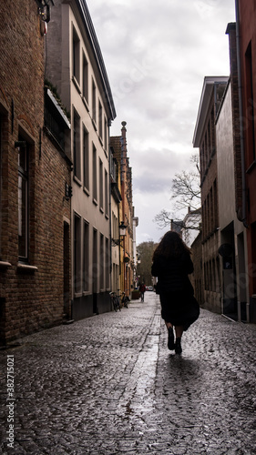 Silhouette woman walking in Bruges. Woman walking on the streets during a day with clouds on the sky.