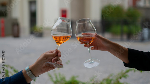 young couple toasting with glasses of rosé wine at the table outside the restaurant.