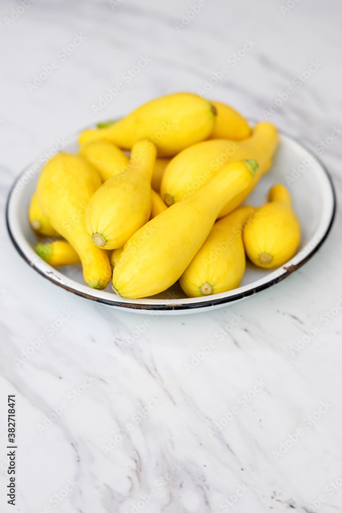 Fresh Yellow Summer Squash in a White Bowl on a Marble Countertop