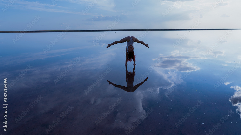 reflection in water woman performs handstand 