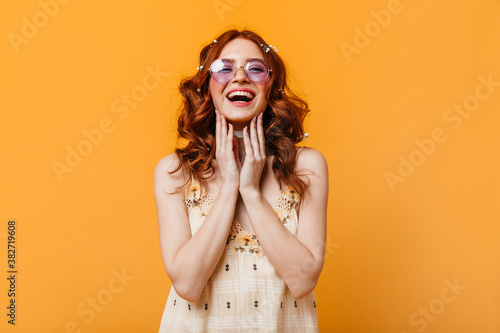 Optimistic girl with curly hair sincerely laughs. Woman in sunglasses and yellow top looking at camera