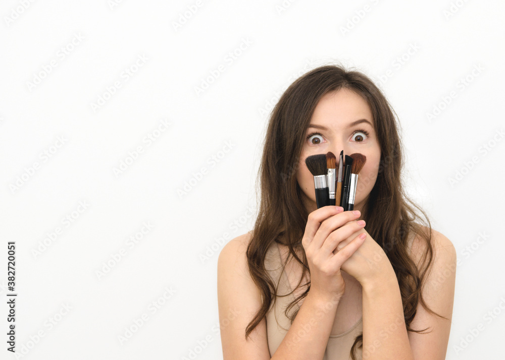 a young beautiful woman brunette with long hair holds make-up brushes a young beautiful woman brunette with long hair holds make-up brushes