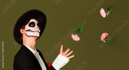 Cheerful zombie man in white shirt throwing flowers. Indoor photo of blithesome guy with red rose.