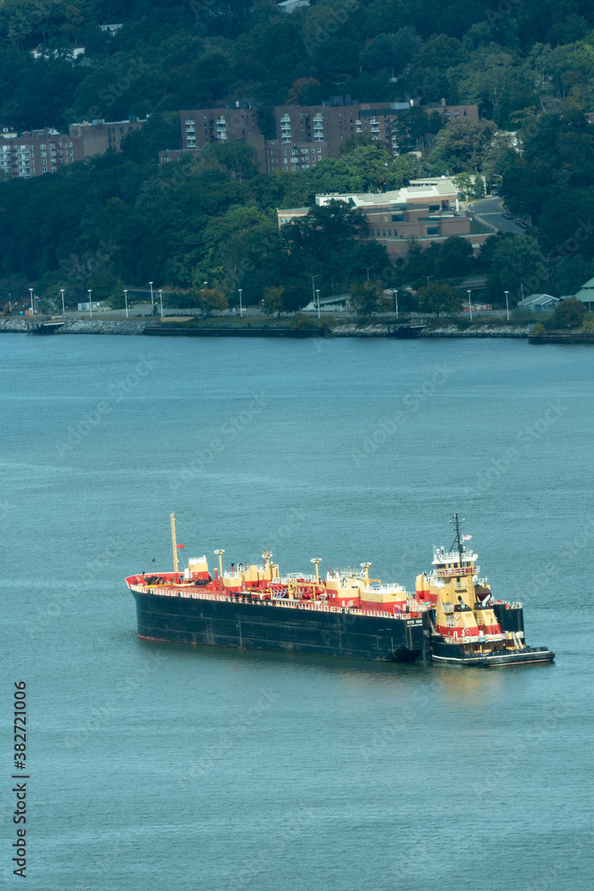 Yonkers, NY / United States - Oct. 6, 2020: a vertical view of a double hull Reinauer Transportation Company barge, pushed up the Hudson River by 7,200-hp tugboat Meredith C. Reinauer