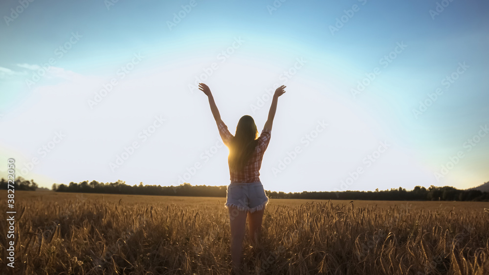 Happy woman walking on a wheat field with open arms at the bright sun. Happy woman walking on a wheat field with open arms at the bright sun.