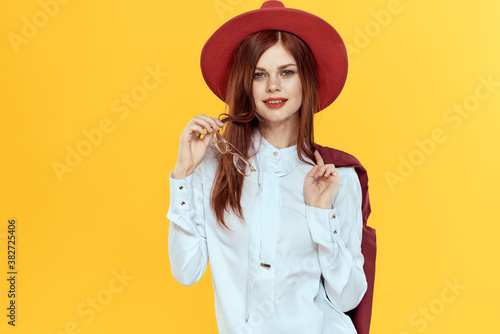 Woman with a jacket on her shoulders red hat white shirt elegant style yellow background