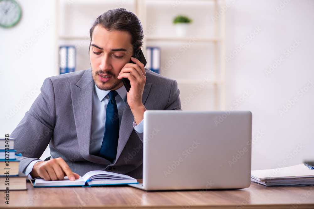 Young male businessman reading books at workplace Young male businessman reading books at workplace