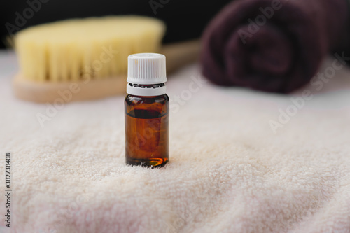 ESSENTIAL OIL in a dark bottle, white towel, body brush, copy space, spa procedures products, eco cosmetic, essential oil glass bottle