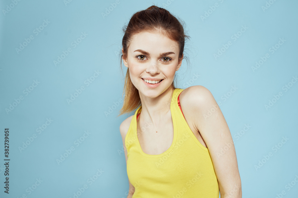 Sportive woman yellow tank top pigtail towards fitness blue background Sportive woman yellow tank top pigtail towards fitness blue background