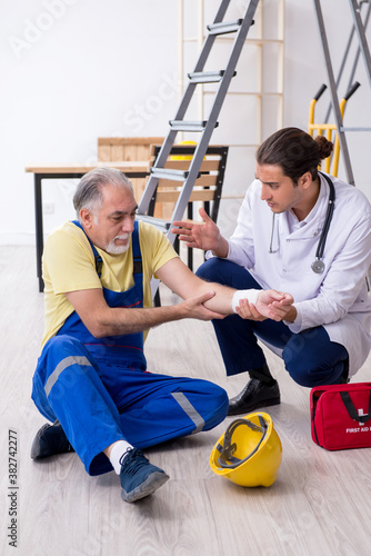 Young male doctor and old contractor in first aid concept
