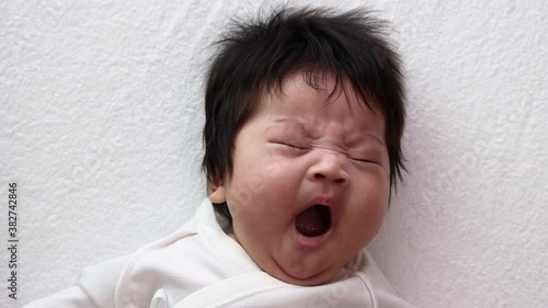 大きな欠伸している生後13週の赤ちゃんの顔