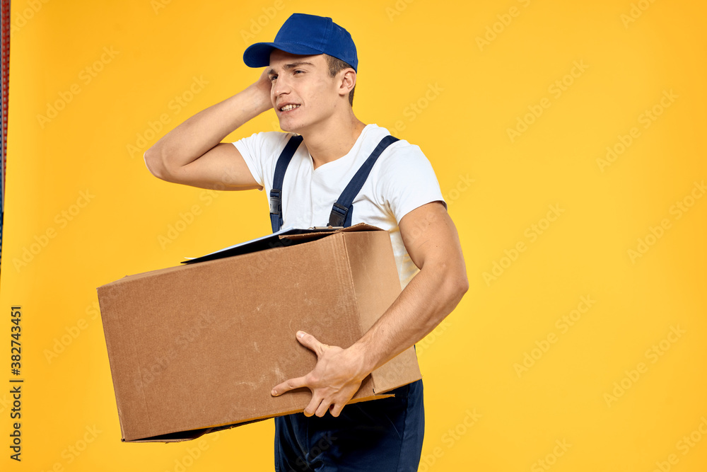 Working man in uniform with box hand delivery loading service yellow background