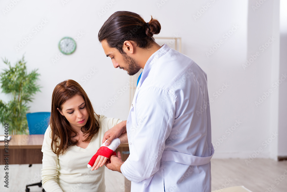 Young hand injured woman visiting male doctor traumatologist