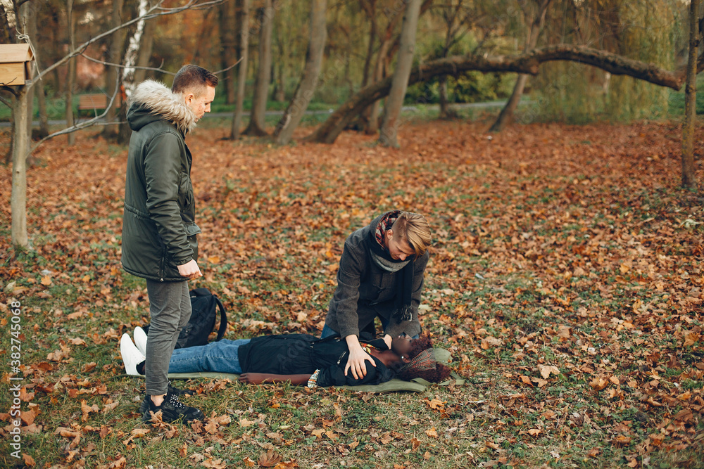 Guys help a woman. African girl is lying unconscious. Providing first aid in the park. Guys help a woman. African girl is lying unconscious. Providing first aid in the park.