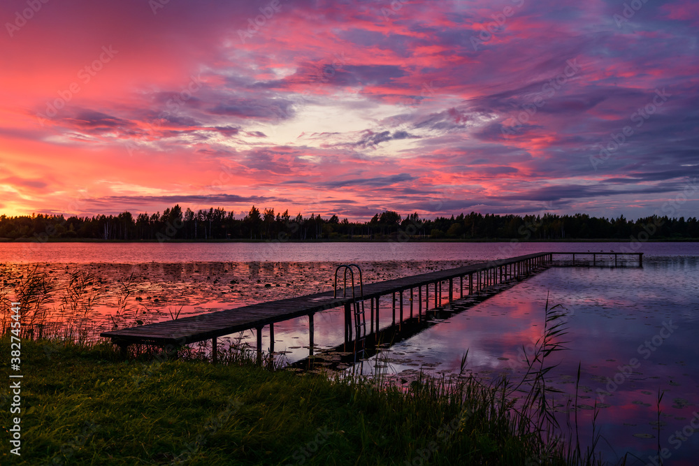 Fototapeta premium Incredible sunset landscape with a wooden pier on a stunning forest lake
