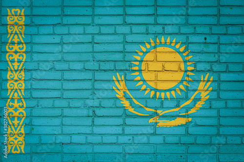 National flag of Kazakhstan depicting in paint colors on an old brick wall. Flag banner on brick wall background.