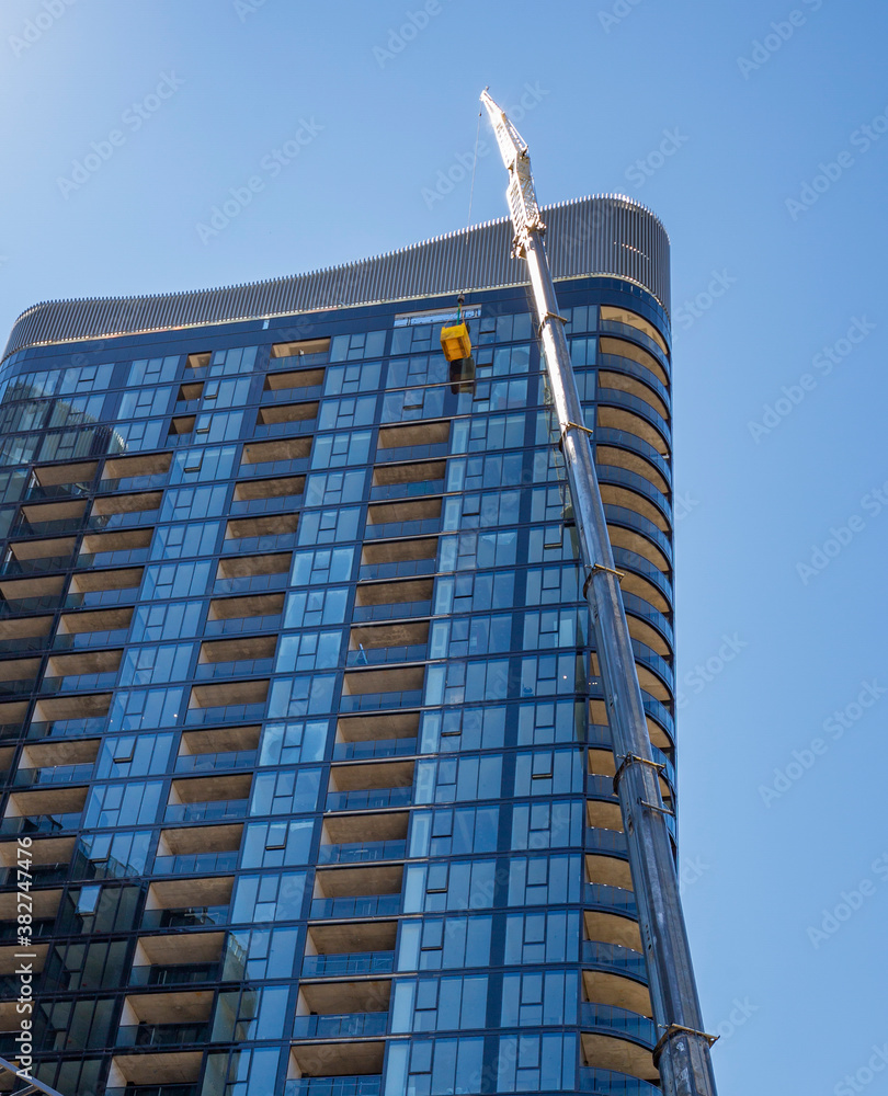 Obraz premium A person working up on a high rise crane cradle on the side of a tall building 