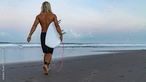 A surfer walking in from the water after a day out on the waves in Bali, Indonesia.Bali, Indonesia