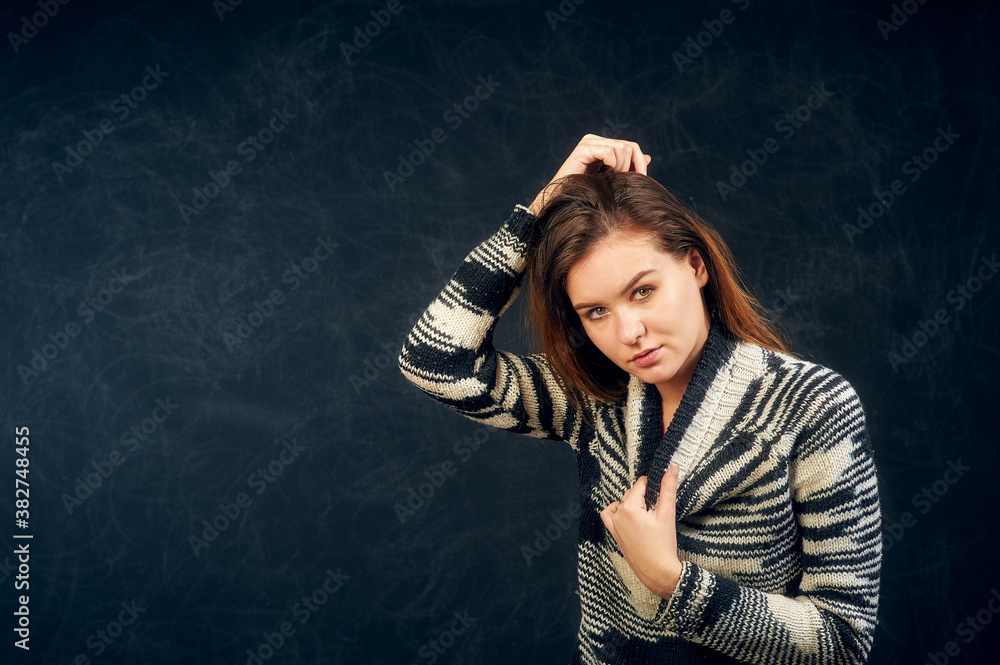 Portrait of a young beautiful girl in a warm knitted sweater on a dark background Portrait of a young beautiful girl in a warm knitted sweater on a dark background