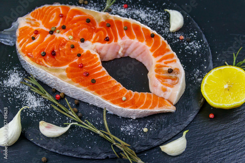 Raw salmon steak with spices on black slate