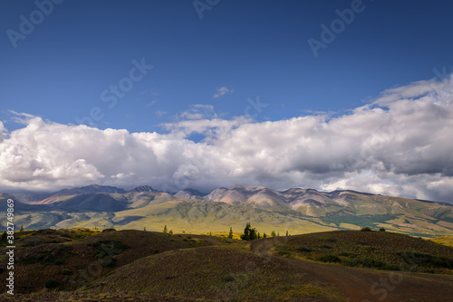 Stunning mountain landscape. Thunderstorm front over the mountain range, sun's rays shine through fluffy clouds. Beautiful sky. Road trips, off-road in Altai, Siberia.