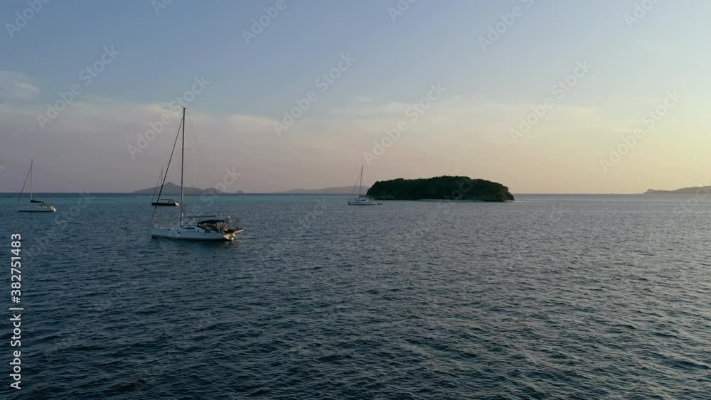 Aerial, pov, boats anchored off the coast of a small island at sunset, South Grenadine Islands Aerial, pov, boats anchored off the coast of a small island at sunset, South Grenadine Islands
