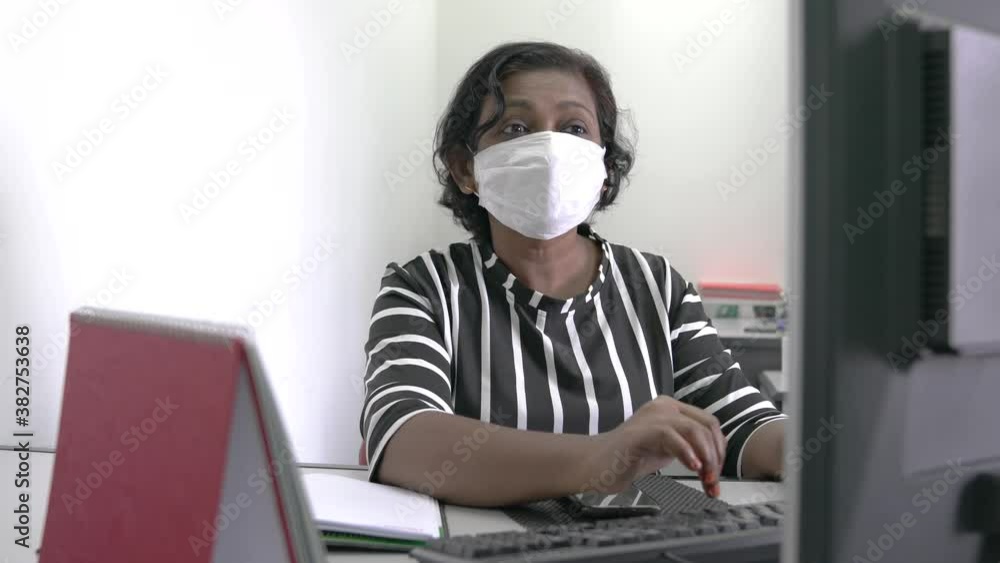 Woman wearing face mask typing on her computer keyboard. Work place during coronavirus pandemic concept. Woman wearing face mask typing on her computer keyboard. Work place during coronavirus pandemic concept.