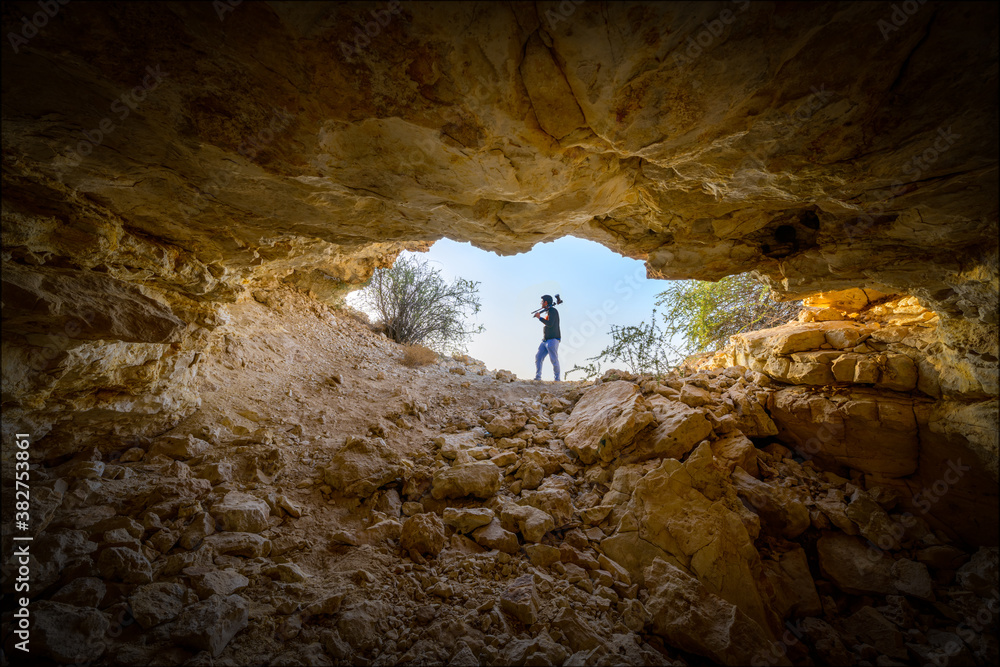 Silhouette of an unidentified photographer standing in front of a cave entrance.