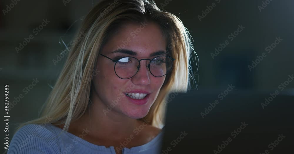 Authentic shot of an young successful businesswoman wearing glasses is smiling satisfied with her work while working with computer in the office at night. Authentic shot of an young successful businesswoman wearing glasses is smiling satisfied with her work while working with computer in the office at night.
