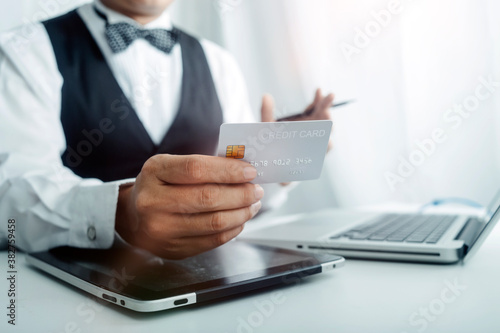 Business people use tablets and hold credit cards as an online shopping concept With a calculator and a book placed on the table © ARMMY PICCA
