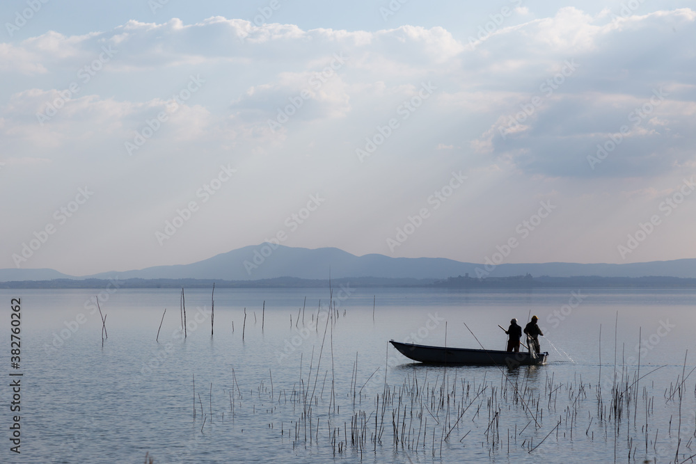 Two men on a little boat fishing in a lake Two men on a little boat fishing in a lake