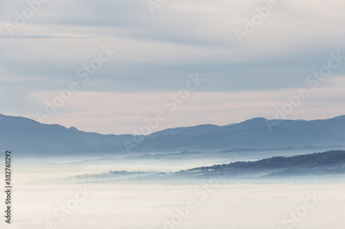 Fog filling a valley in Umbria (Italy) at dawn, with layers of mountains and hills
