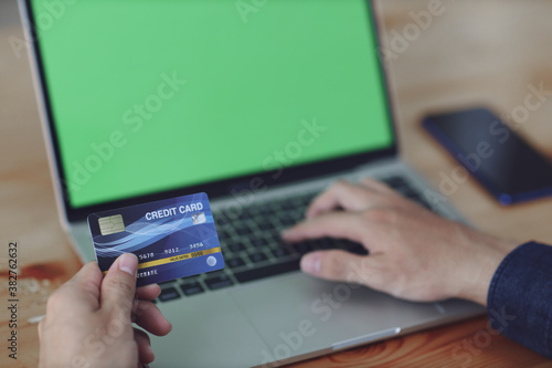 Man using blank laptop and credit card sending massages shopping online.