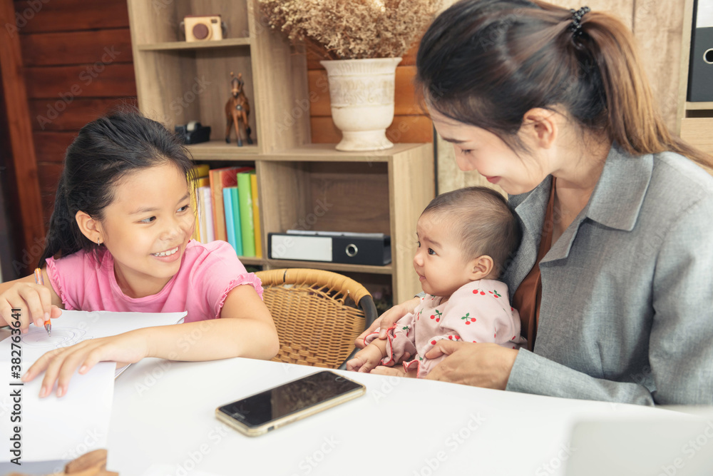 Busy asian woman trying to work while baby sitting two kids. Single mom work from home with the children. Busy asian woman trying to work while baby sitting two kids. Single mom work from home with the children.