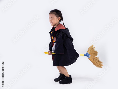 Asian children girl in witch dress costume Riding a broom for Halloween decoration in white background