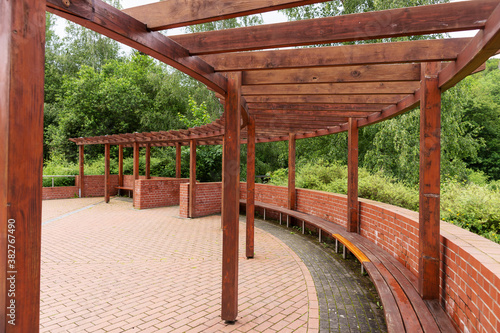 New round wooden pergola with long bench in the park © kelifamily