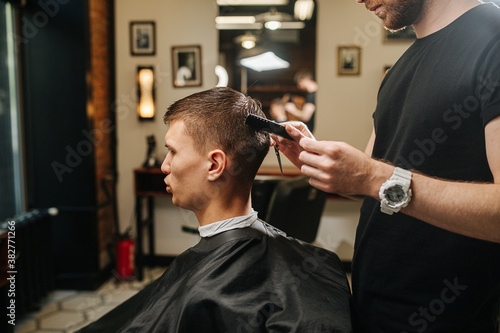 Young man in a barber shop getting a haircut. Side view.