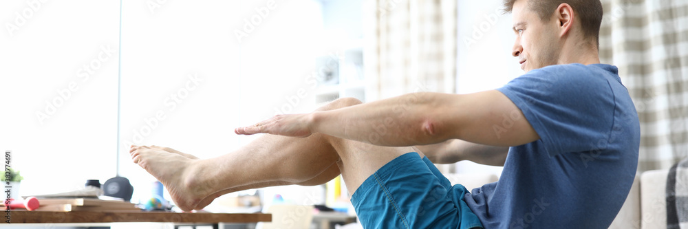 Obraz premium Close-up of man doing push-ups at home. Male wearing comfy sportswear and training indoors on quarantine period. Healthy strong and fit body. Sport and active lifestyle concept